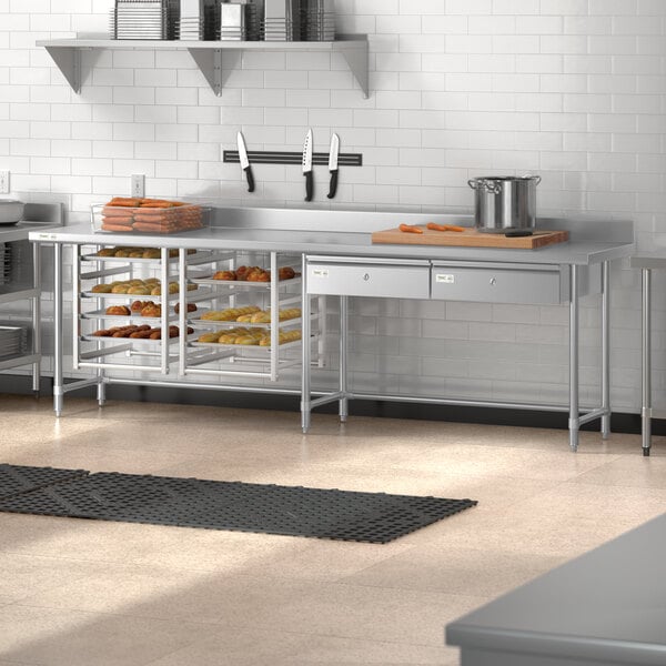 A Regency stainless steel open base work table with a backsplash in a large kitchen.