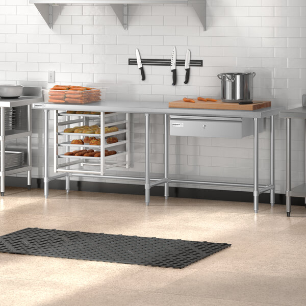 A Regency stainless steel open base work table in a kitchen with shelves.