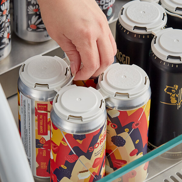 A hand opening a PakTech white plastic 4-pack can carrier with a can of soda inside.