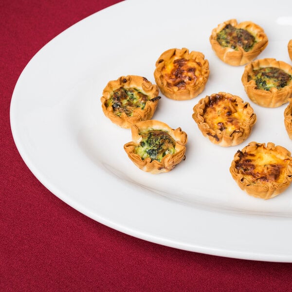 A Tuxton bright white china platter with mini quiches.