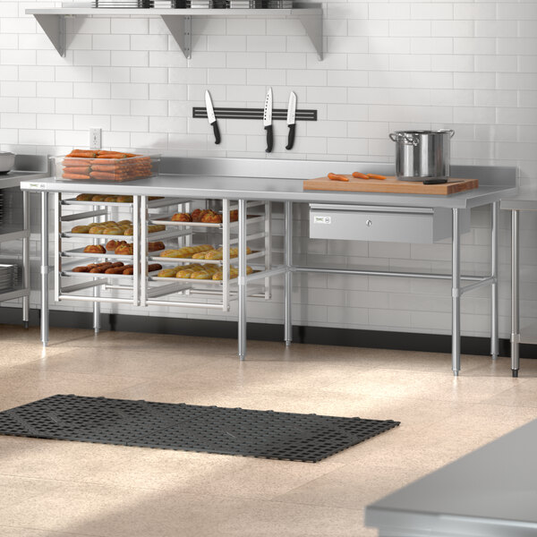 A Regency stainless steel open base work table in a kitchen with a large tray of food on it.