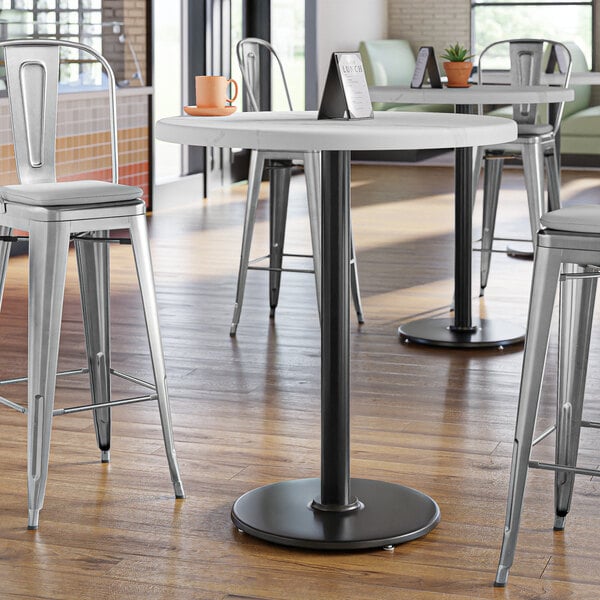 A Lancaster Table & Seating black cast iron bar height table base with a round table top.