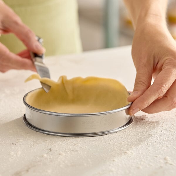 A round stainless steel deep tart ring being used to shape dough.