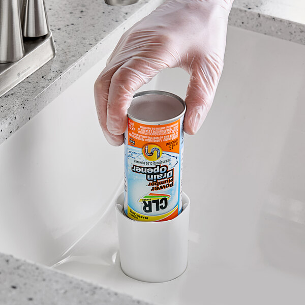 A gloved hand using CLR PRO Pressurized Drain Opener in a professional kitchen sink.