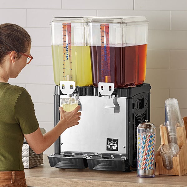 A woman pouring a drink into a Carnival King refrigerated beverage dispenser.