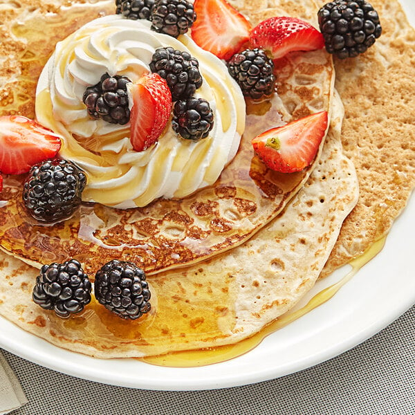 A plate of pancakes topped with strawberries and whipped cream.