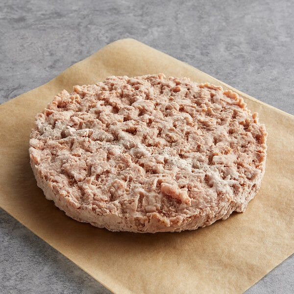 A raw Beyond Meat plant-based vegan burger patty on a brown paper.