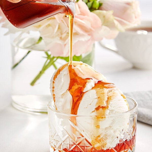 A glass cup with a scoop of ice cream and Runamok Rum Barrel-Aged Maple Syrup being poured into it.