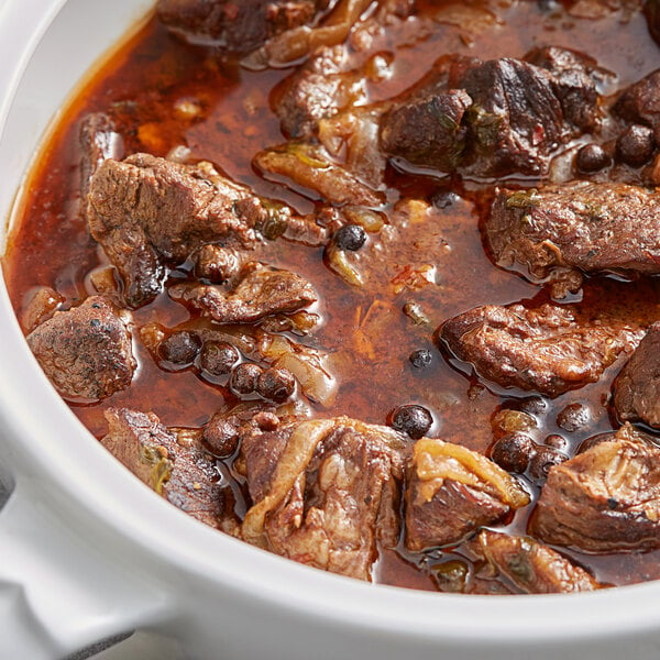 A bowl of stew with meat and vegetables and beans.