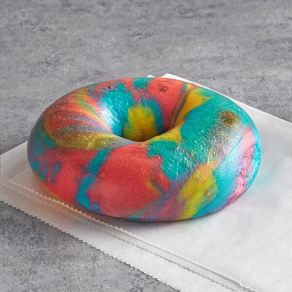 A colorful bagel with a tie dye design on a white surface.