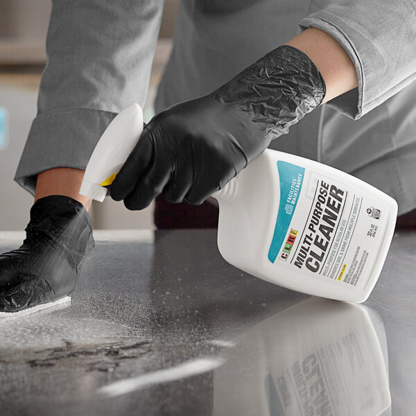 A person in black gloves spraying CLR Multi-Purpose Cleaner on a counter.