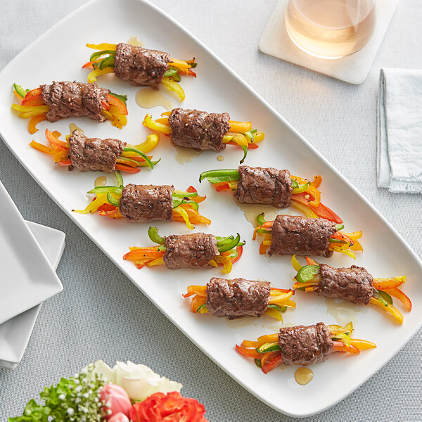 A plate of food with meat wrapped in peppers and cheese drizzled with Runamok Maple Syrup on a table.