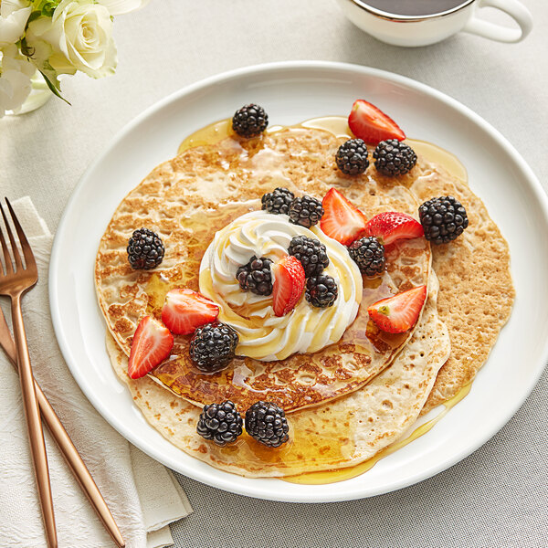 A plate of pancakes topped with strawberries and whipped cream.