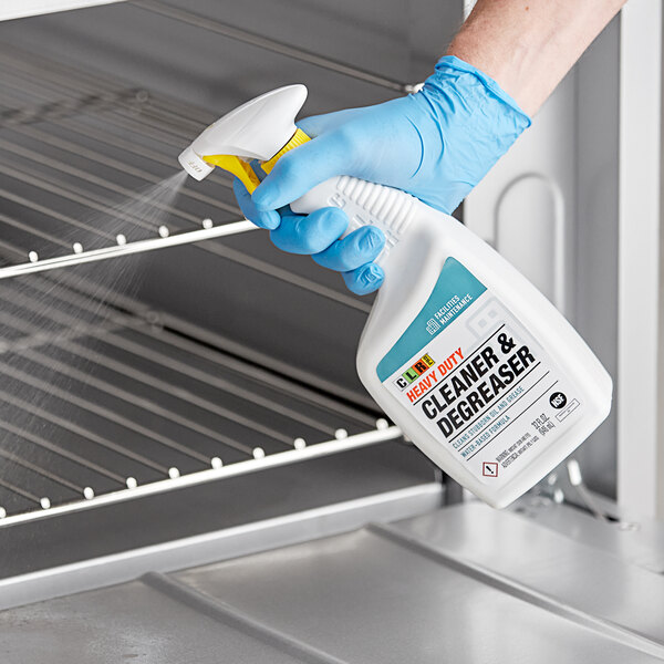 A person in blue gloves using CLR Heavy-Duty Cleaner and Degreaser to spray a professional oven.