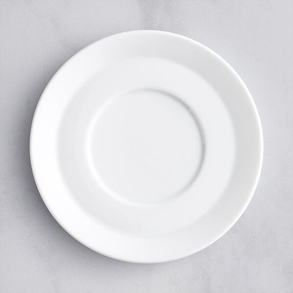 A white porcelain espresso saucer with a circular shape on a grey surface.