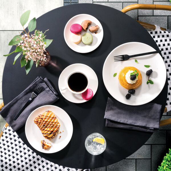 A table with Homer Laughlin Alexa Ameriwhite plates of food and drinks.