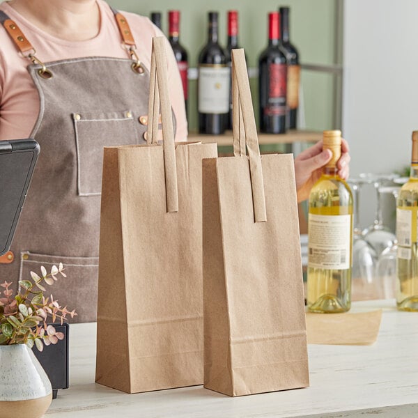 A person behind a counter holding a brown Choice paper bag with two bottles inside.