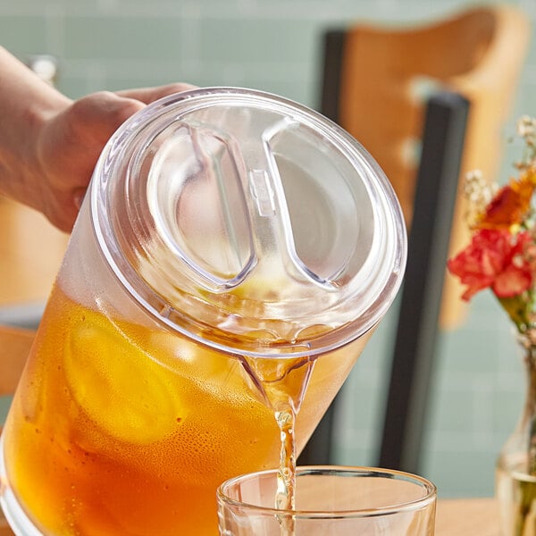 A person pouring a drink from a GET Lid into a glass on a table.