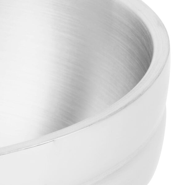 A close up of a Vollrath pearl white metal serving bowl with a beehive design.
