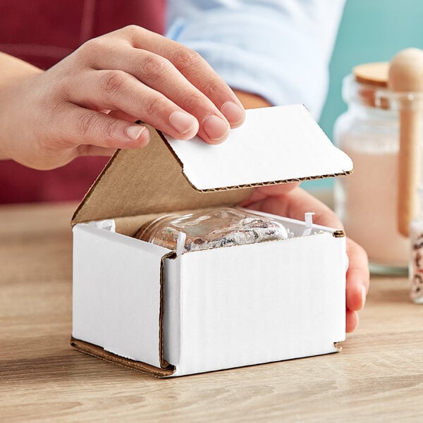 A person opening a small white box.