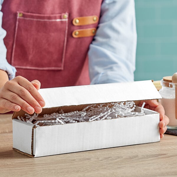 A person holding a white Lavex corrugated mailer box.