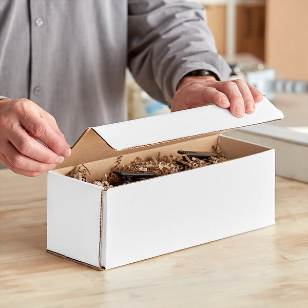 A person opening a white Lavex corrugated mailer box.