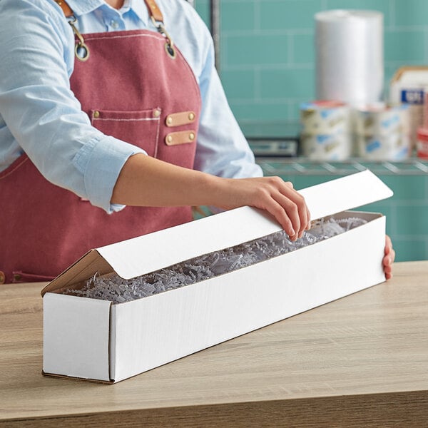 A woman in an apron opening a white Lavex corrugated mailer box.