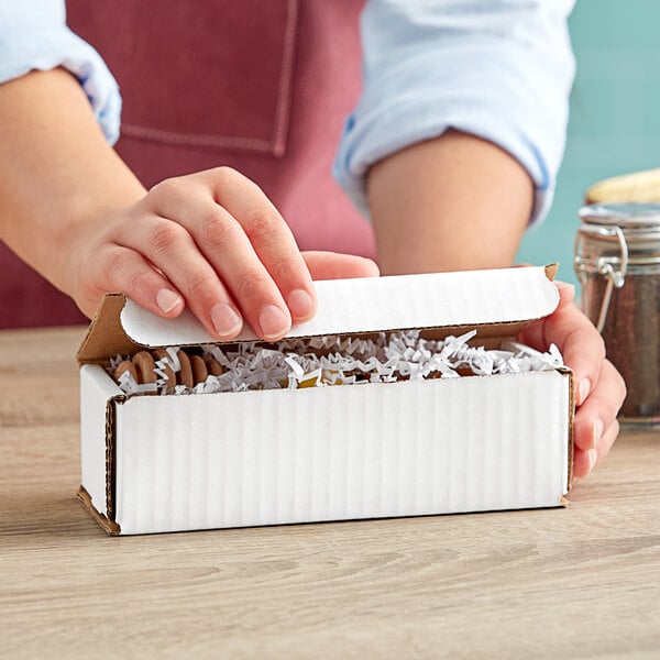 A person opening a white Lavex corrugated mailer box.