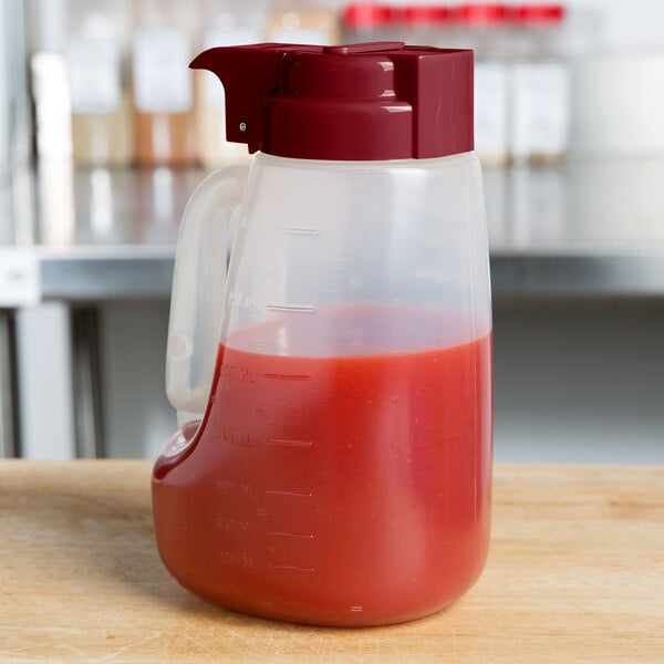 A Tablecraft 32 oz. dispenser jar with a maroon lid filled with red liquid.