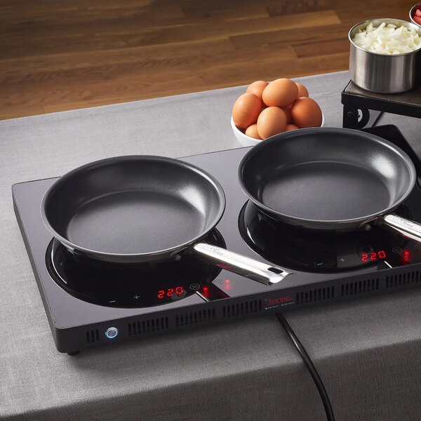 A non-stick fry pan with a stainless steel handle placed on an induction cooktop.