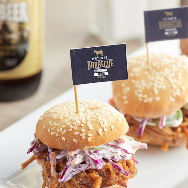 A close-up of a burger with a medium rectangular flag pick with blue trim.