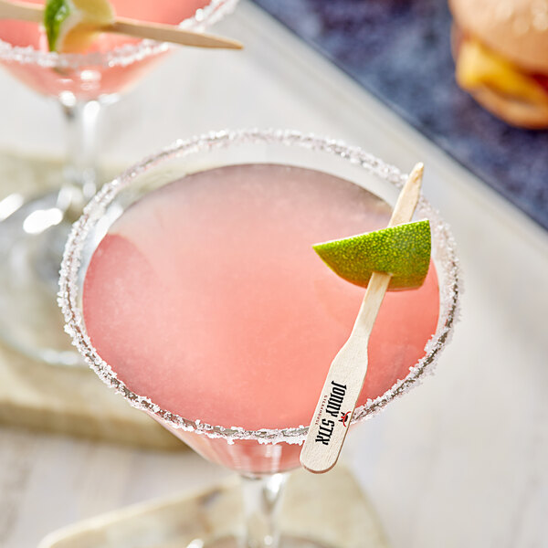 Two pink margaritas with lime wedges garnished with a customizable paddle pick on a table in a cocktail bar.