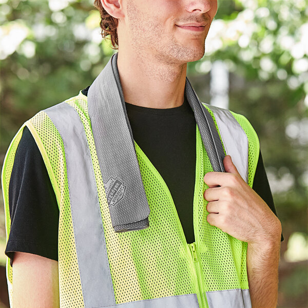 A man wearing a yellow safety vest using an Ergodyne gray evaporative cooling towel.