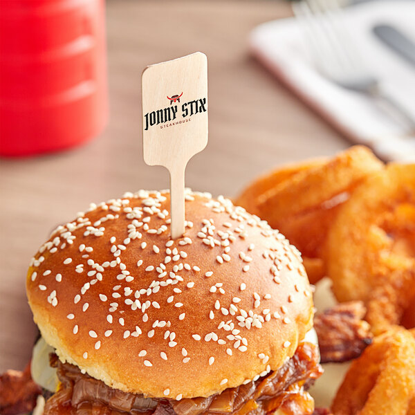 A burger with a customizable rectangle pick on top of the bun with sesame seeds.