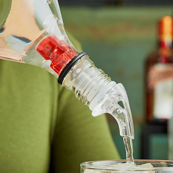 A woman using a Choice 3-ball measured liquor pourer to pour liquid into a glass.