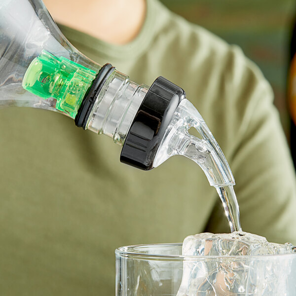 A person using a Choice 3-Ball Measured Liquor Pourer to pour a drink into a glass.