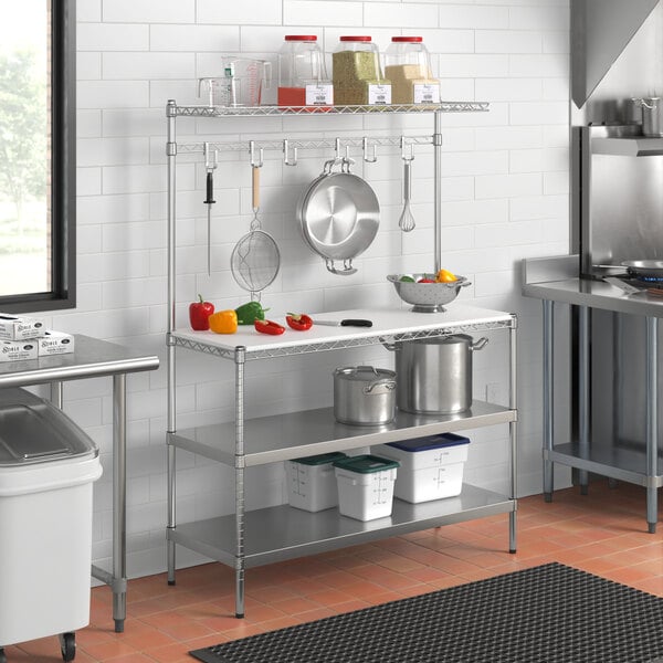 A Regency stainless steel baker's rack with a white plastic cutting board on a shelf.