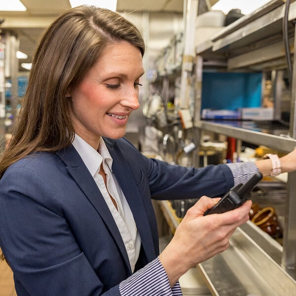 A person in business attire using a Midland FRS two-way business radio in a commercial kitchen setting.