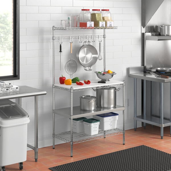 A Regency baker's rack with metal and stainless steel shelves and a plastic cutting board on a kitchen counter.