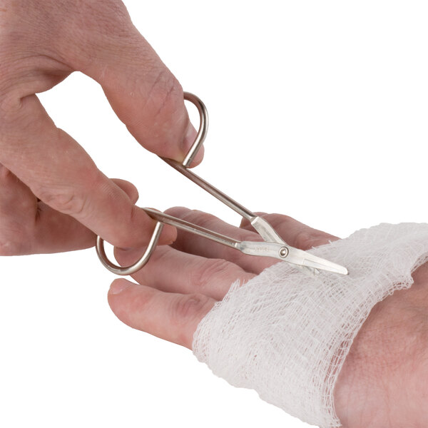 A person using Medique wire scissors to cut a bandage on a hand.