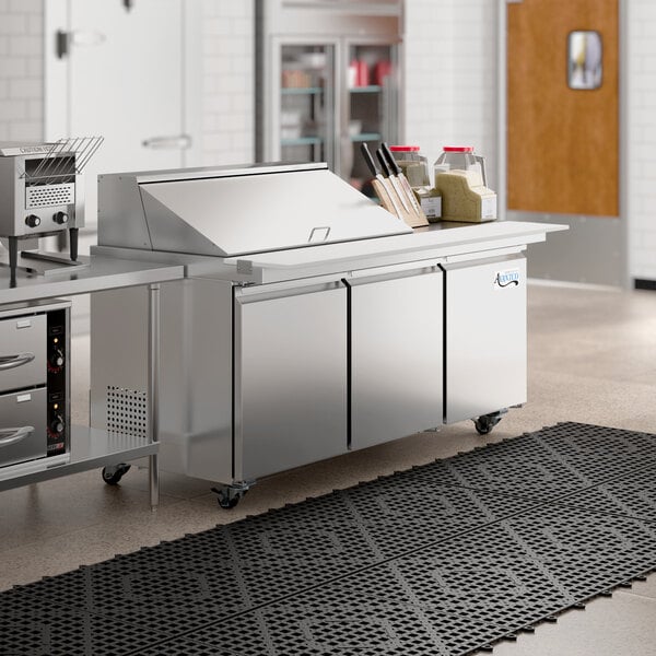 An Avantco stainless steel sandwich prep table on a large stainless steel counter.