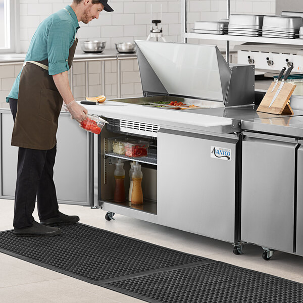 An Avantco stainless steel ADA height sandwich prep table with extra deep cutting board on a counter in a kitchen.