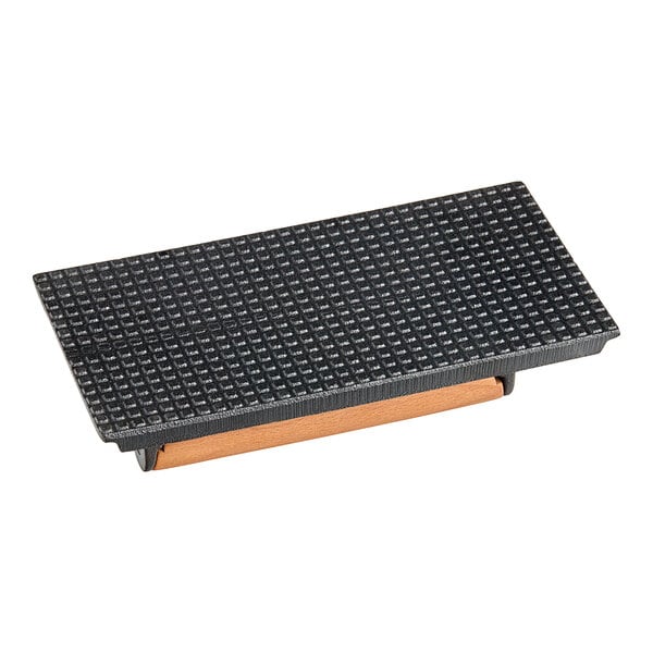 An American Metalcraft cast iron steak weight on a black rectangular object with a wooden frame.