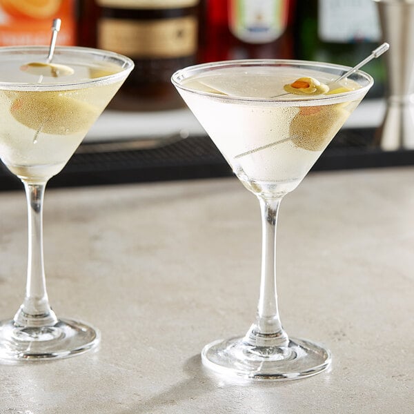 A table with two Acopa martini glasses filled with drinks, each garnished with an olive.