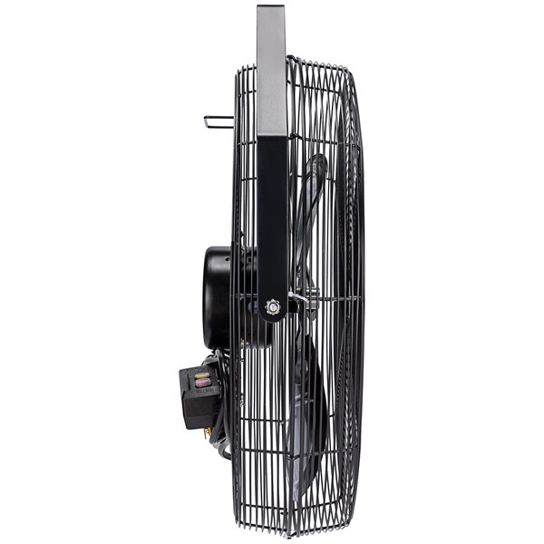 A close-up of a black Tornado metal wall fan with a metal cage.