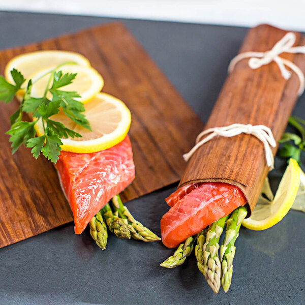 Two pieces of salmon wrapped in Wildwood Grilling cedar wraps with lemon slices.