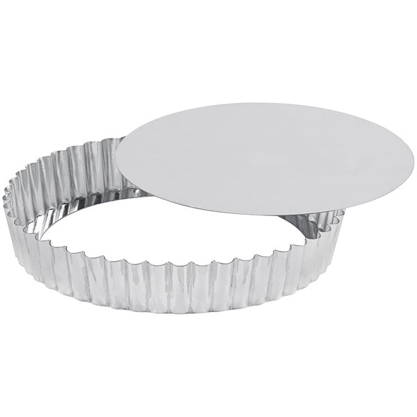 A close-up of a silver Gobel round fluted tart pan with a removable bottom.