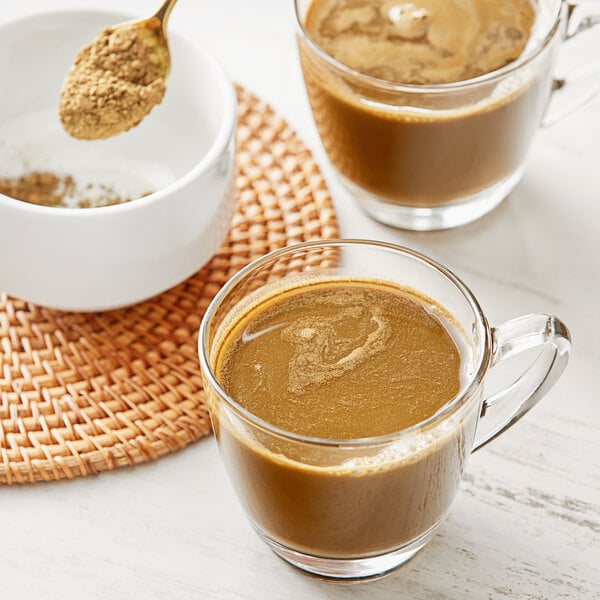 A spoonful of Jade Leaf Organic Hojicha Barista Edition Roasted Green Tea Powder in a glass mug of brown liquid.