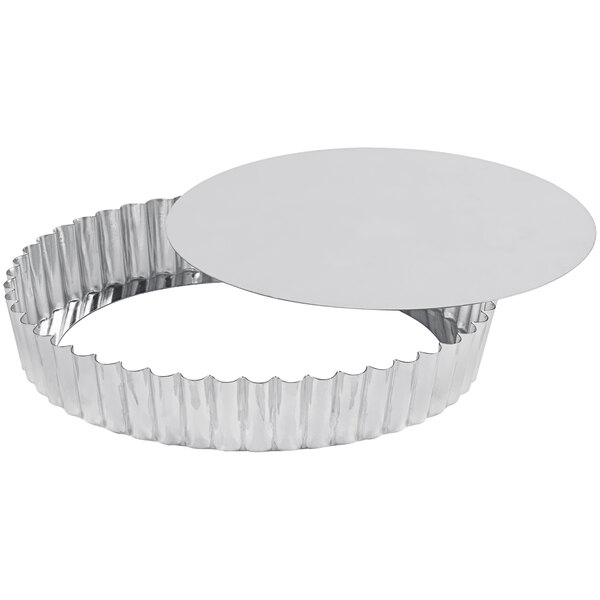 A close-up of a silver Gobel round fluted tart pan with a removable bottom.