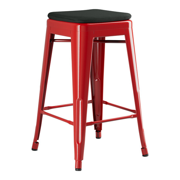 A Lancaster Table & Seating Alloy Series Ruby Red outdoor backless counter height stool with black cushion.